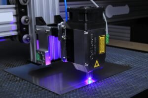 Close-up of a laser engraving machine operating on a metal surface with blue laser light.